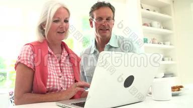 中年夫妇看着笔记本电脑吃早餐